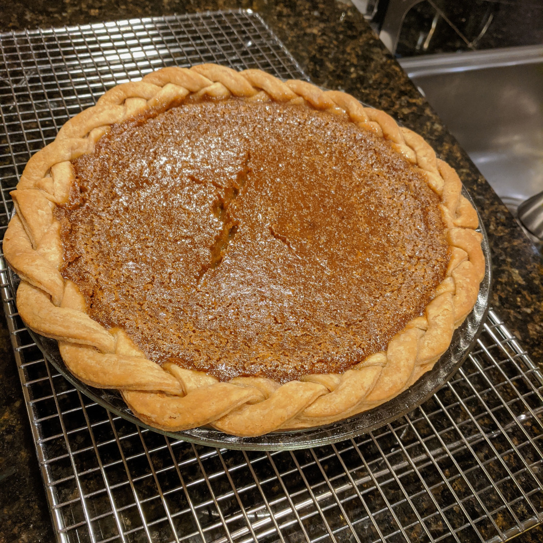 A pumpkin pie with braided crust and a cracked custard