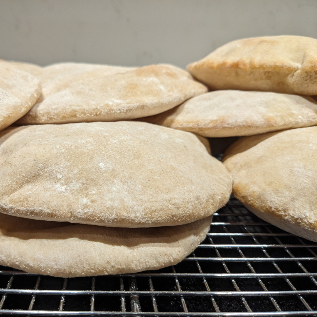 Fresh pita breads cooling in a pile on a rack