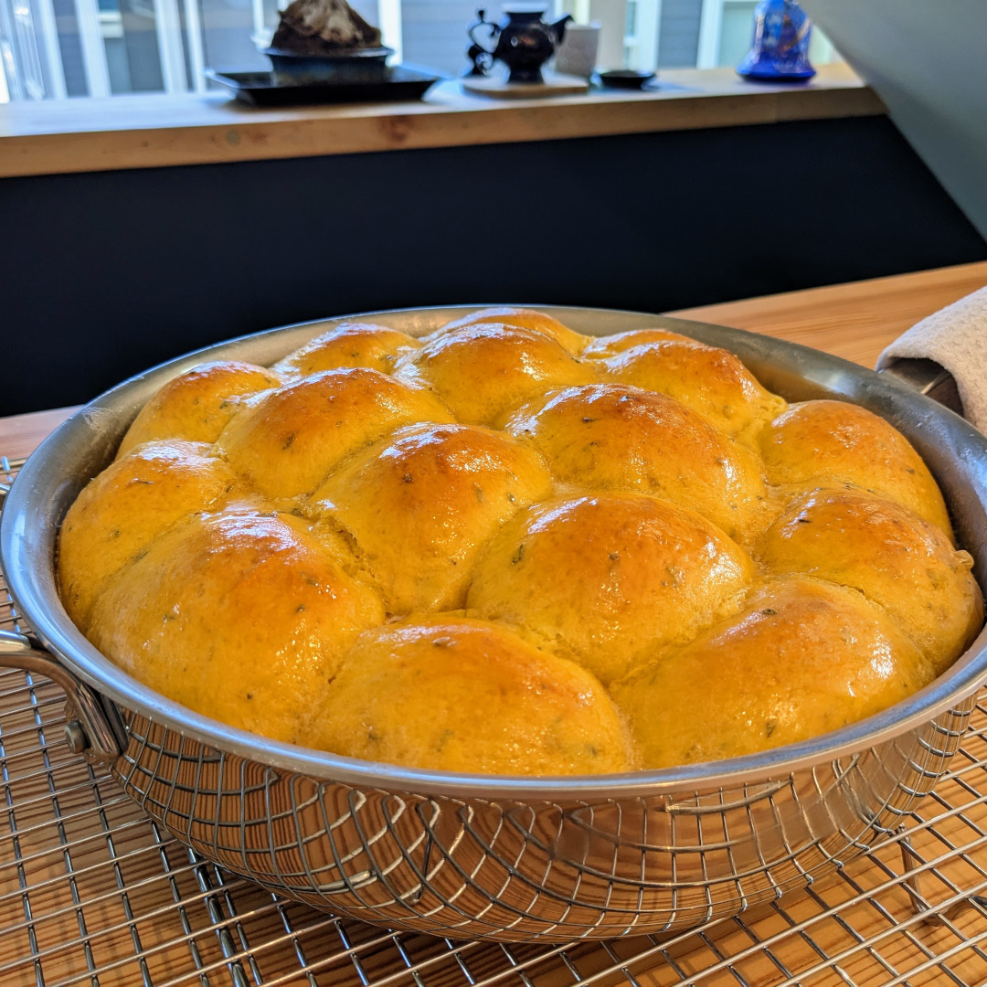 Batch baked dinner rolls in a stainless steel saute pan
